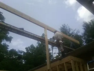 Carpenter setting a ridge beam over a new addition frame — Ice Dam Removal by Roofing Brothers in Riceville