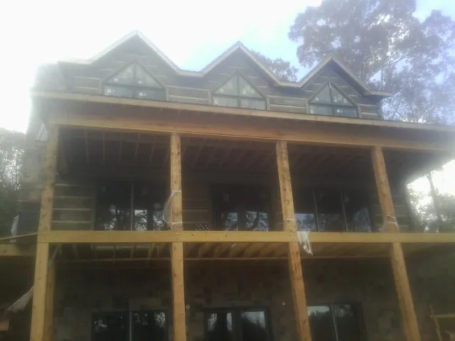 Dormers and porch framing on a large log home under construction — Roof Coating work by our crew in Riceville