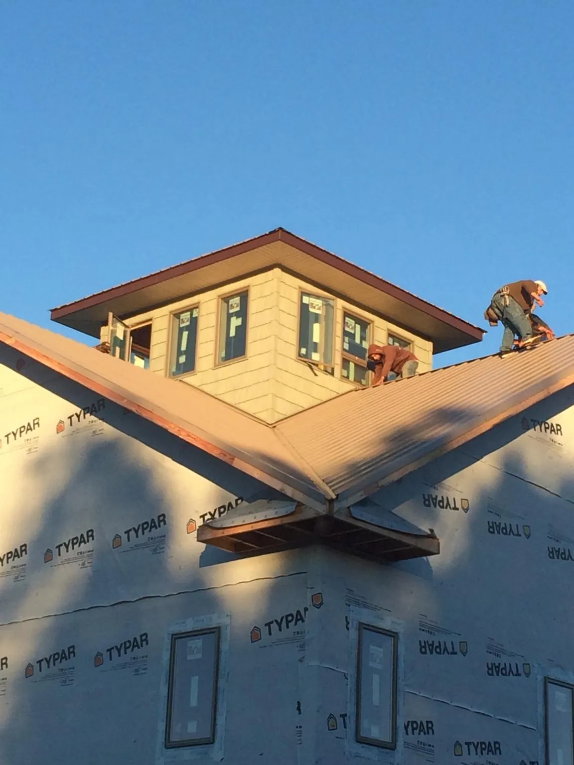 Roofers working around a rooftop cupola on a new metal roof at sunset — Roof Waterproofing in Riceville by Roofing Brothers